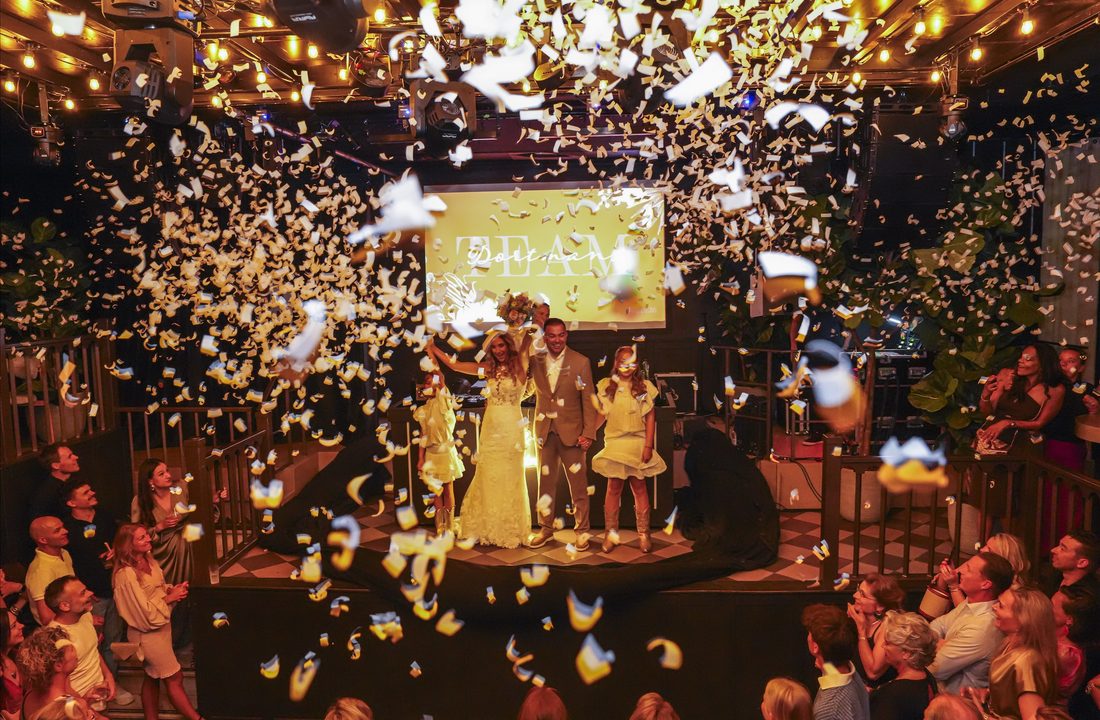 Bruidspaar en kinderen tussen de confetti tijdens een feestelijke bruiloft