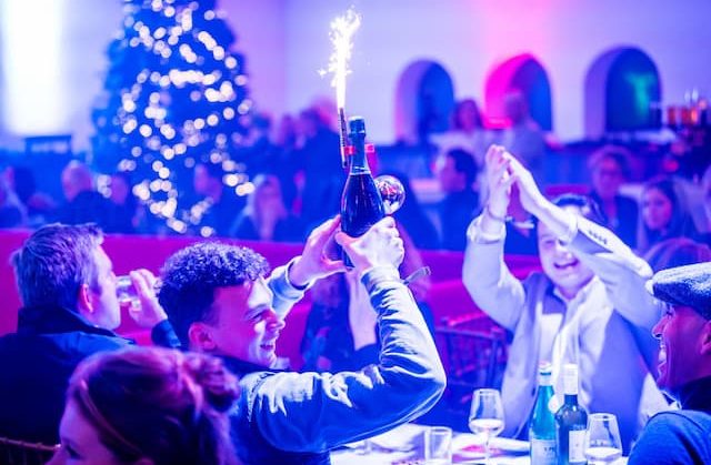 Feestende gasten met een fles bubbels en sterretje tijdens een dinnershow