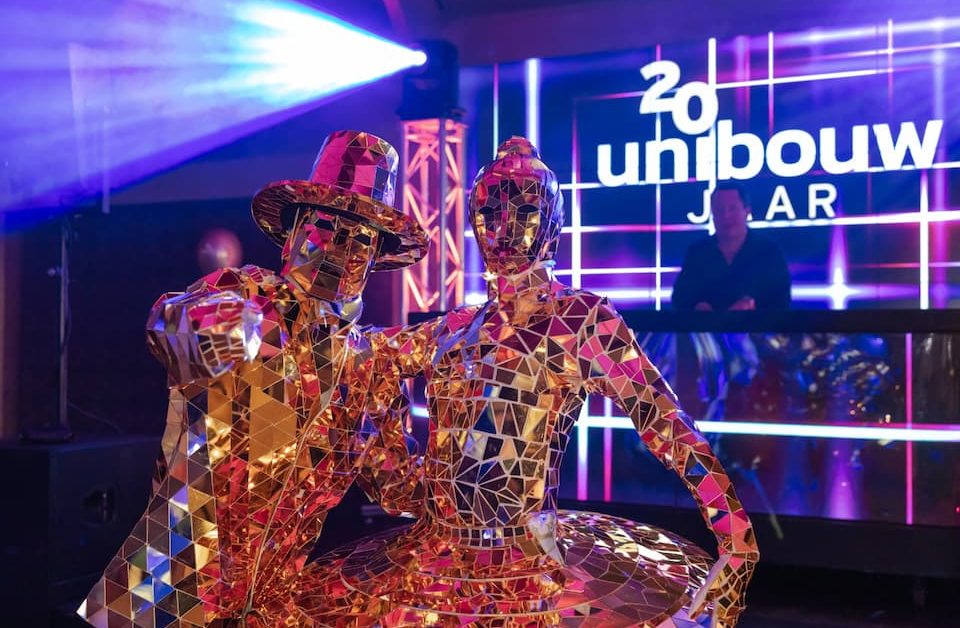 Artiesten in spiegelkostuums tijdens een kleurrijk personeelsfeest