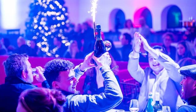 Feestende gasten met een fles bubbels en sterretje tijdens een dinnershow