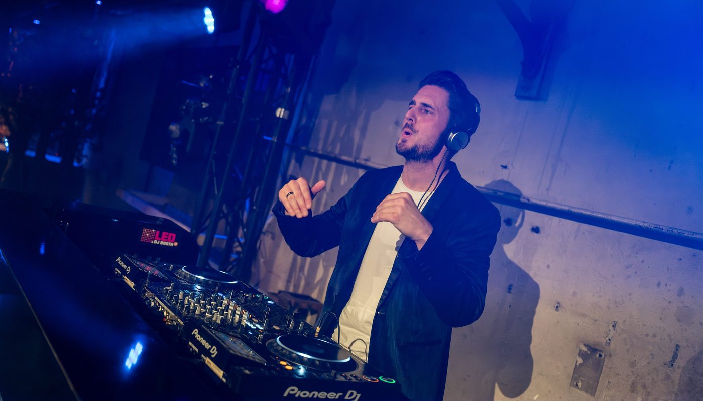 DJ achter professionele apparatuur in blauw en paars podiumlicht
